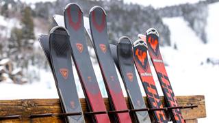 Rossignol skis leaning against ski rack outside.