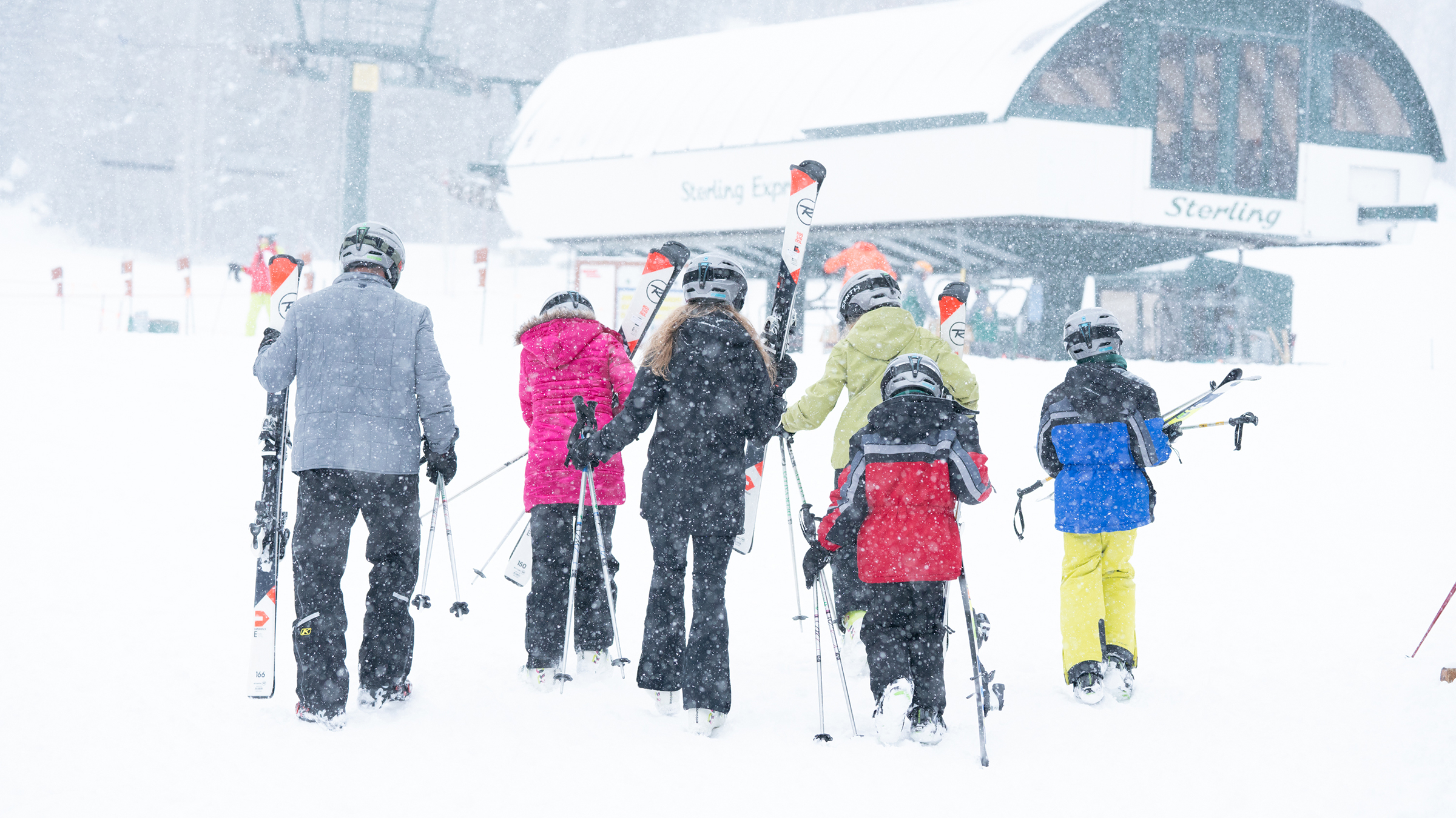 A family walking to Sterling Express Chairlift with ski rentals