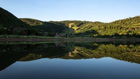 Summer view of a picturesque pond with a reflection of Deer Valley's base area.
