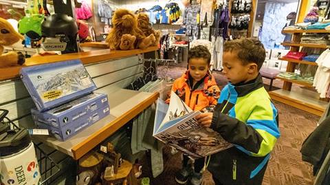 Two kids looking at book inside Deer Valley retail store. 