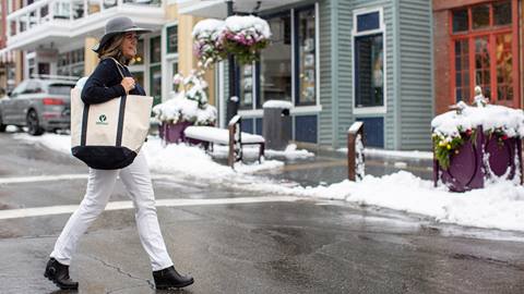 Woman crossing Main Street carrying a Deer Valley bag.