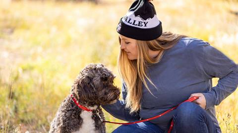 Woman wearing Deer Valley apparel walking a dog.