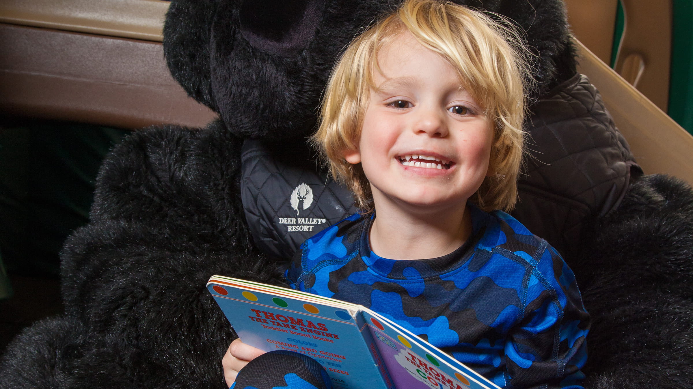 Boy smiling and reading a book.