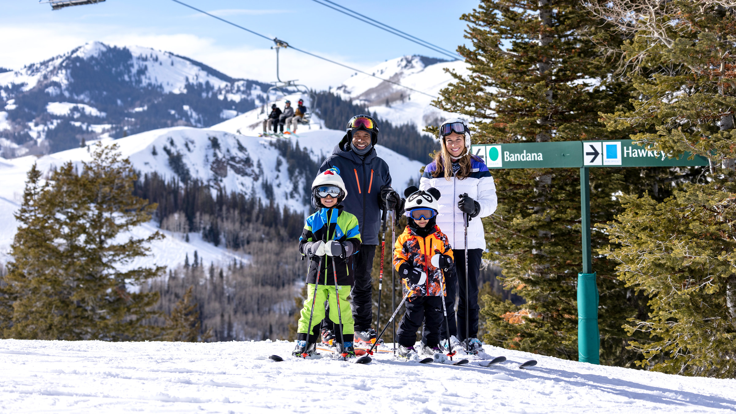 Family of four skiing smiling for a photo while wearing skis.