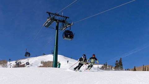Skiers below Deer Valley East Village Gondola on a sunny day.
