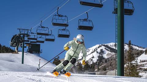 Woman skiing a groomed run under a chairlift at Deer Valley.