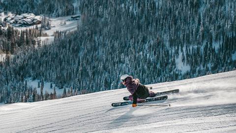 a skier with a deer valley resort lift ticket makes a deep carving turn on a groomed ski run 