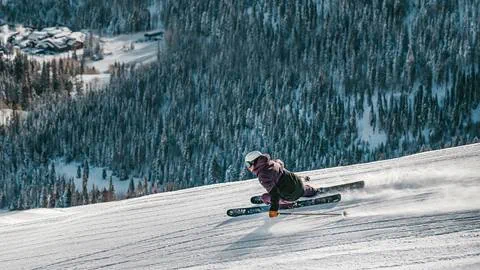 a skier with a deer valley resort lift ticket makes a deep carving turn on a groomed ski run 