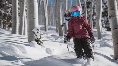 Young girl skiing powder through trees at Deer Valley.