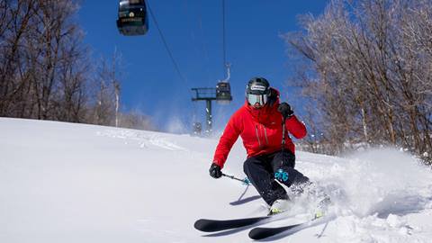 Man skiing powder under Jordanelle Express Gondola.