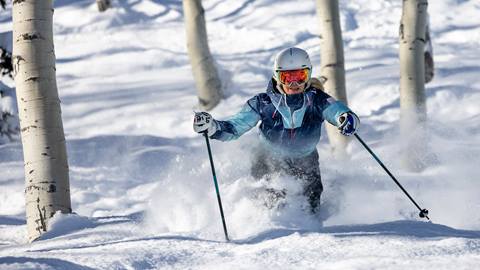Woman powder skiing through trees at Deer Valley.
