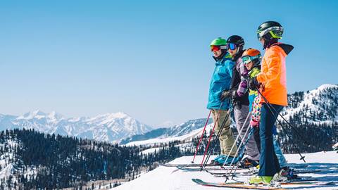 Family standing on ski run overlooking view of Deer Valley.