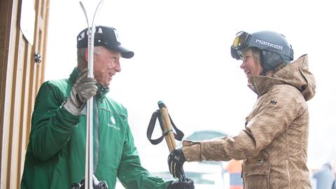 Deer Valley staff helping a female guest store her skis.