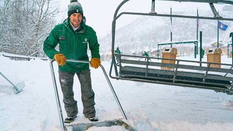 Deer Valley chairlift operator shoveling snow.