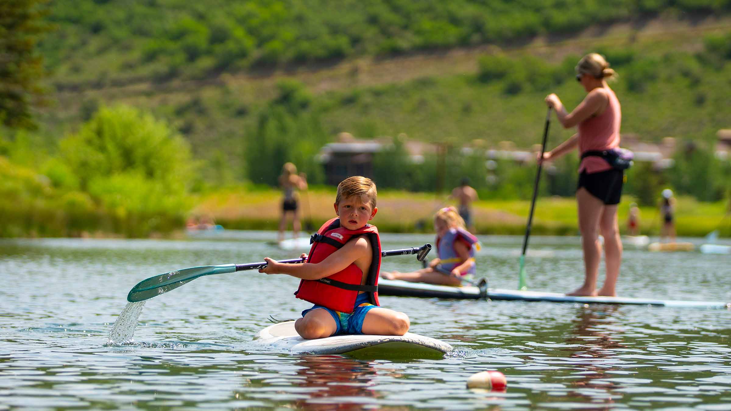 Little boy sitting on paddleboard.