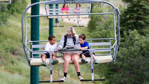 A camp counselor riding a chairlift with two young campers.
