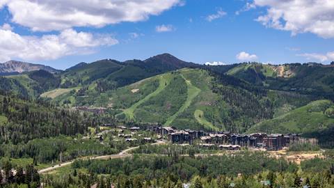 Scenic view of Deer Valley Resort in summer, featuring luxurious properties with a vibrant bluebird sky backdrop.
