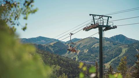 Family on a scenic chairlift ride at Deer Valley in the summer surrounded by mountain views.