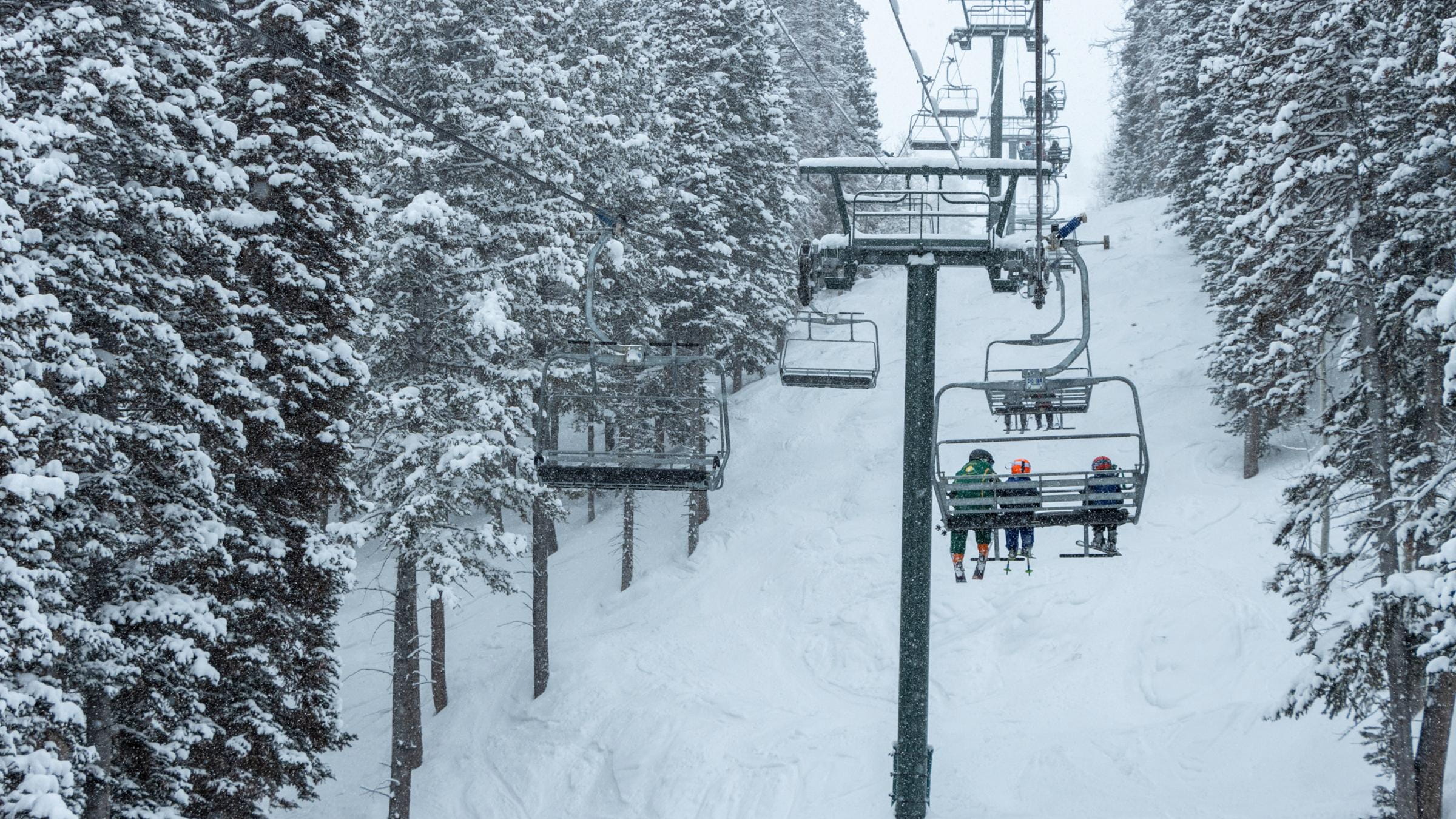 Guests riding up a chairlift at Deer Valley Resort while its snowing