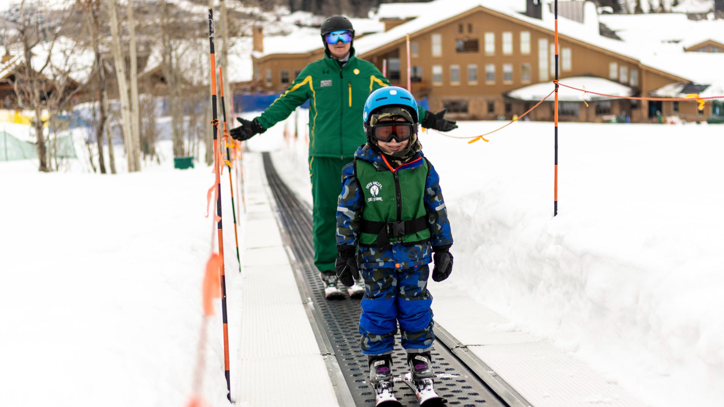 A little boy riding up the conveyor with his instructor smiling