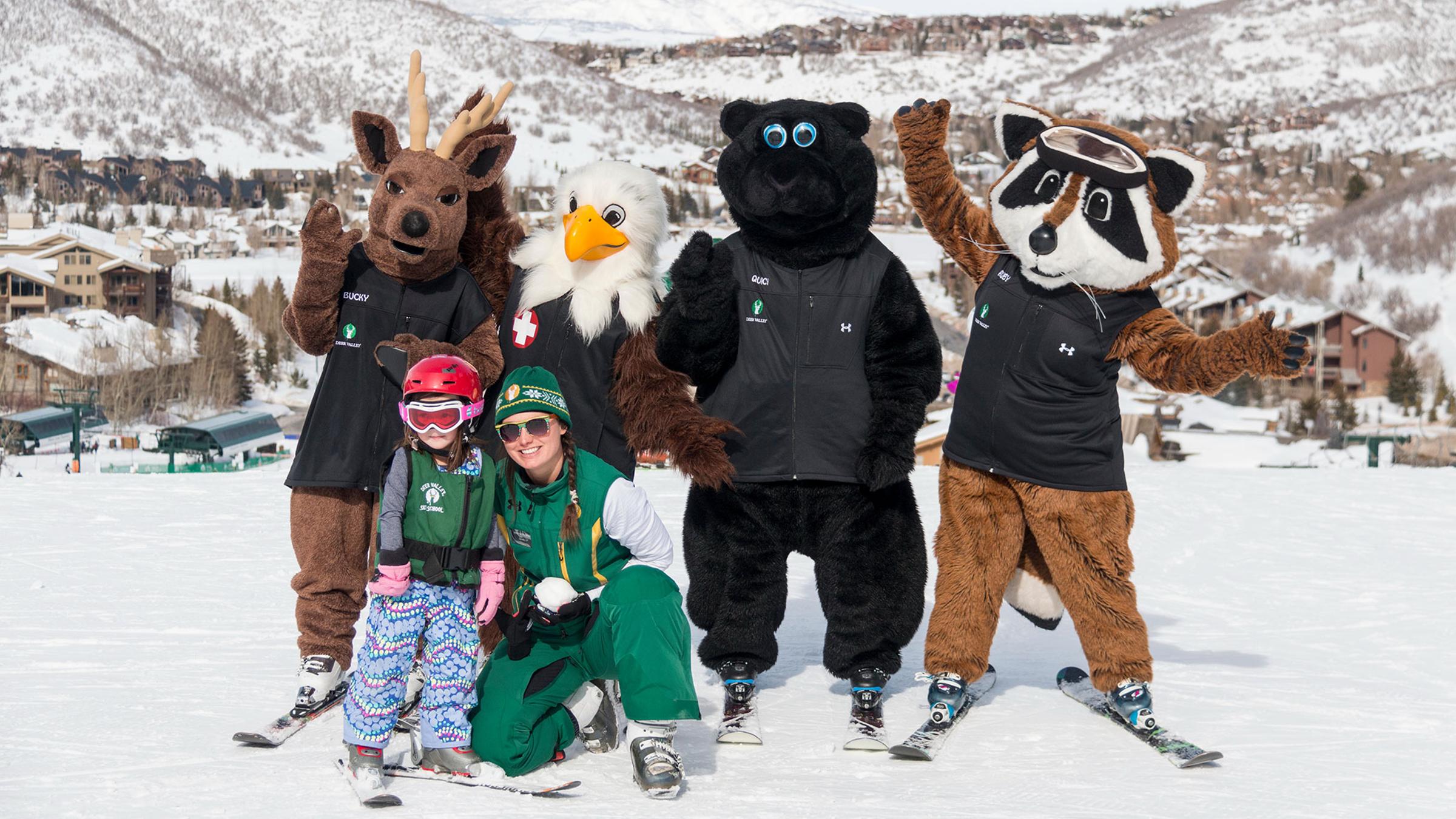 A ski instructor with child and mascots smiling