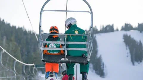 An instructor riding up a chairlift with a student