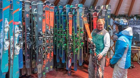 a yurt staff memeber showing a guest skis