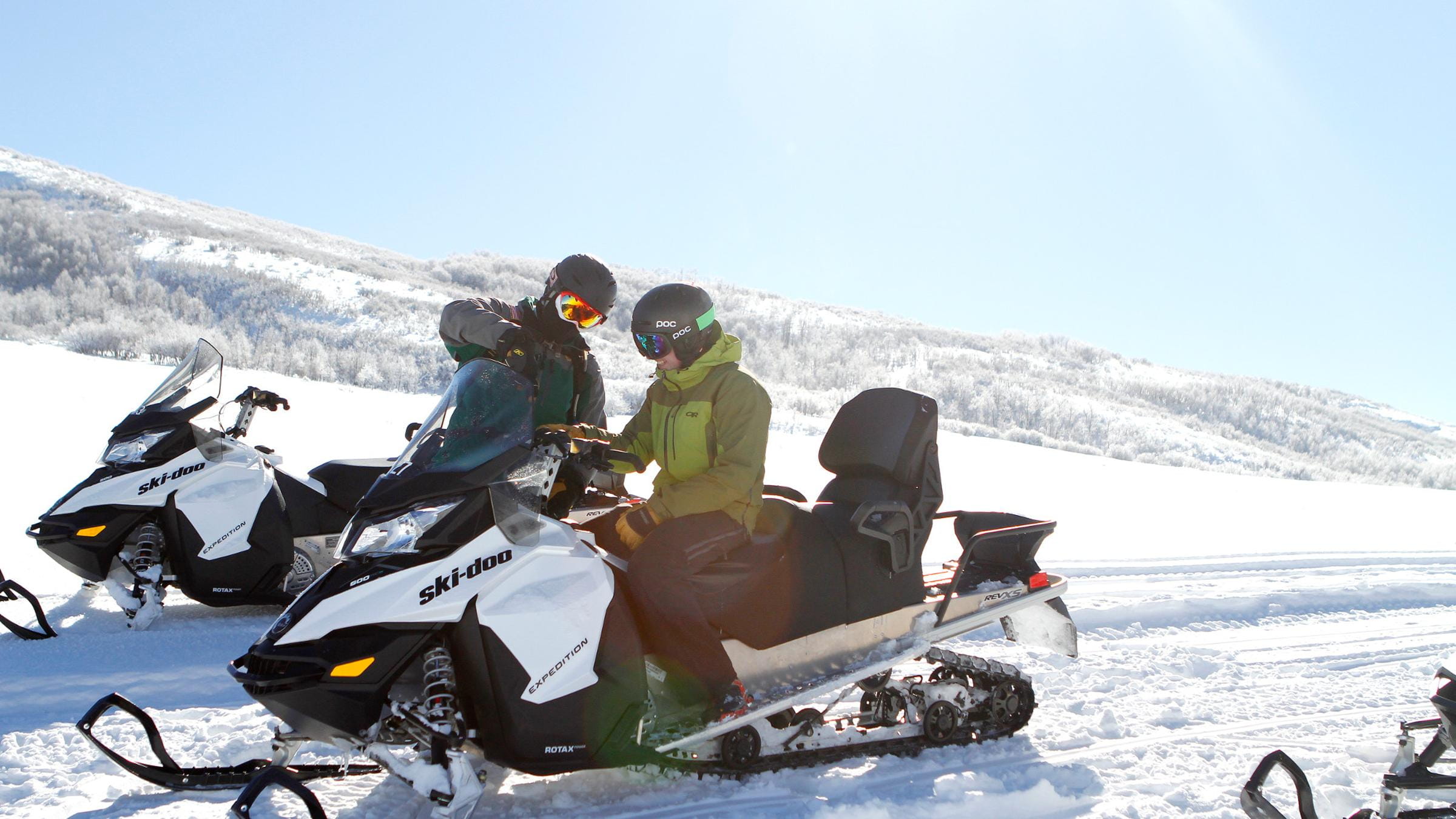 Snowmobile guide showing a guest the snowmobile