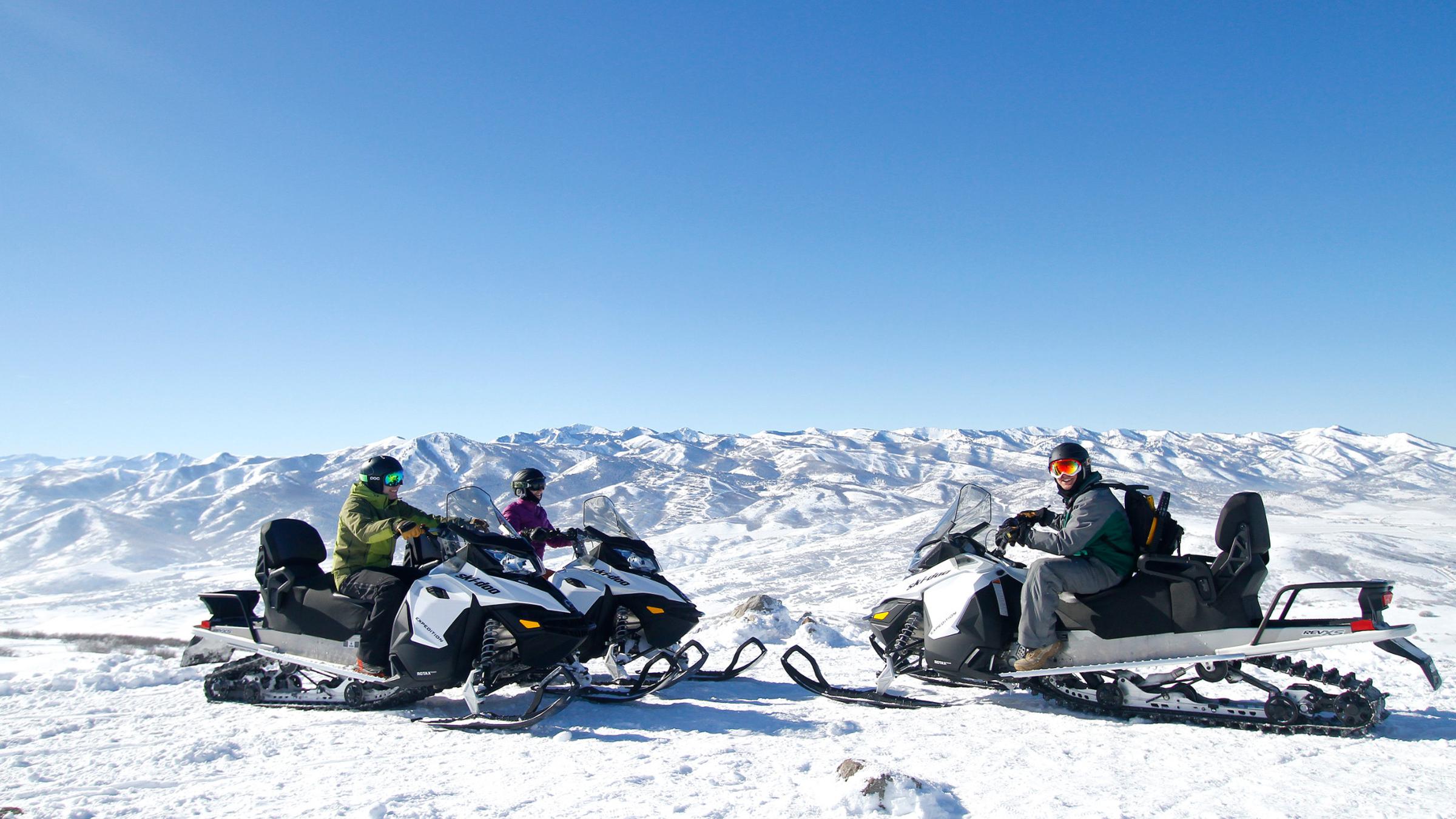 Guests with their snowmobile guide at the top of a snowy mountain