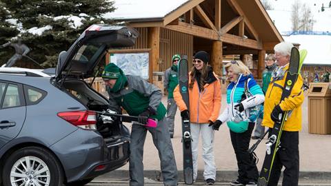 A guest service attendant putting guests skis in their car
