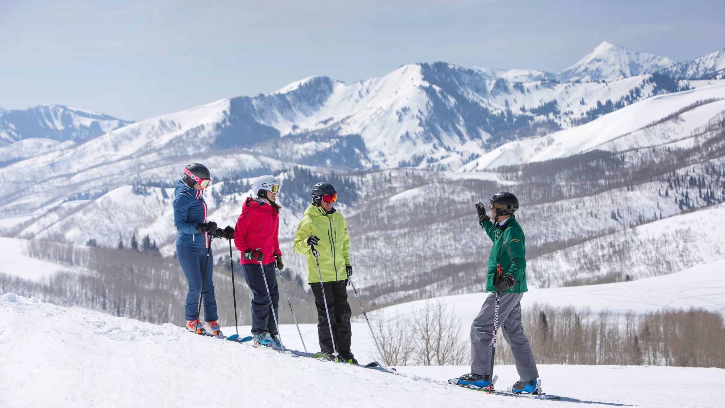 Three guests listening to a mountain host on a ski run