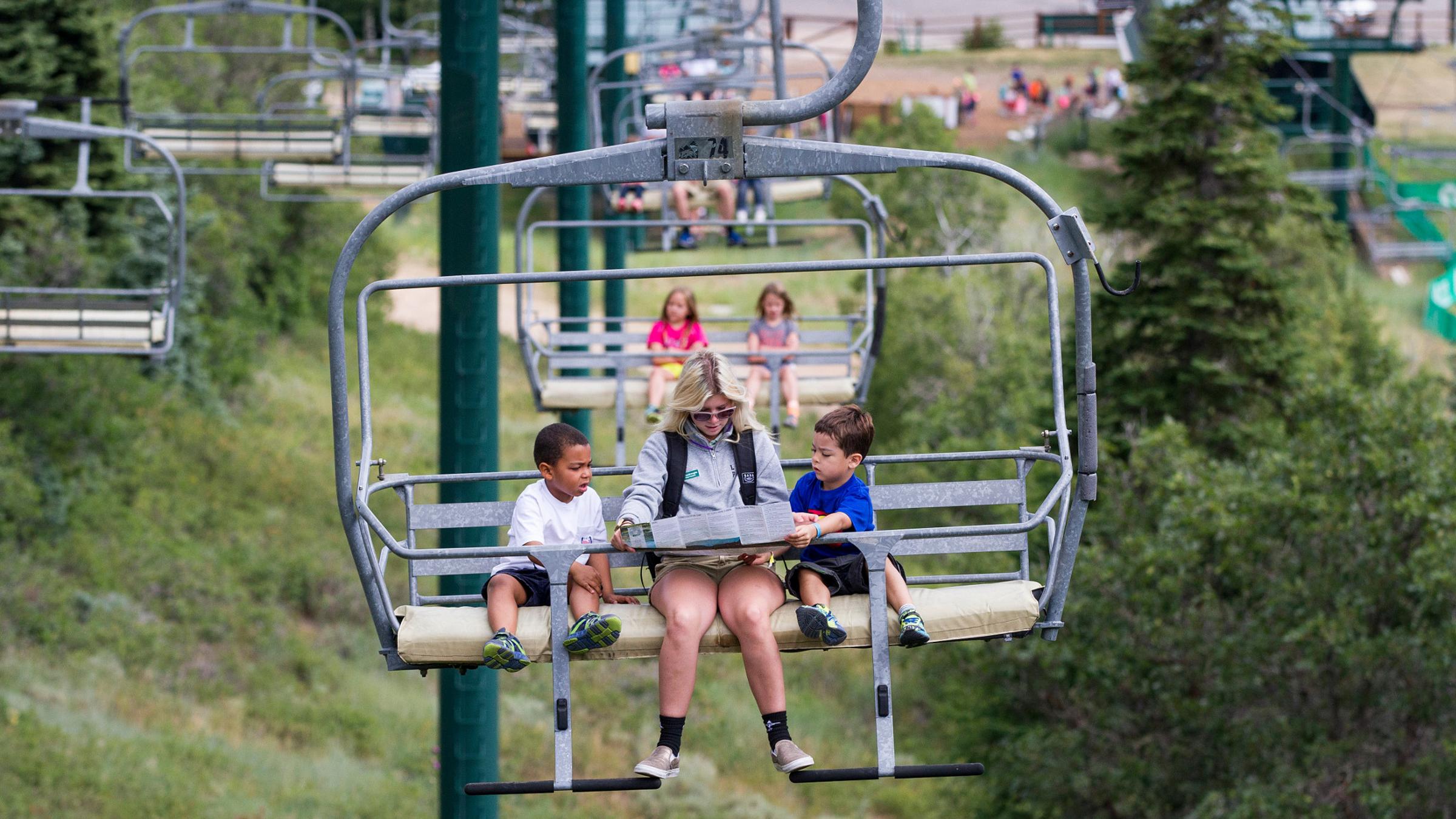 Campers riding on a chairlift with a counselor