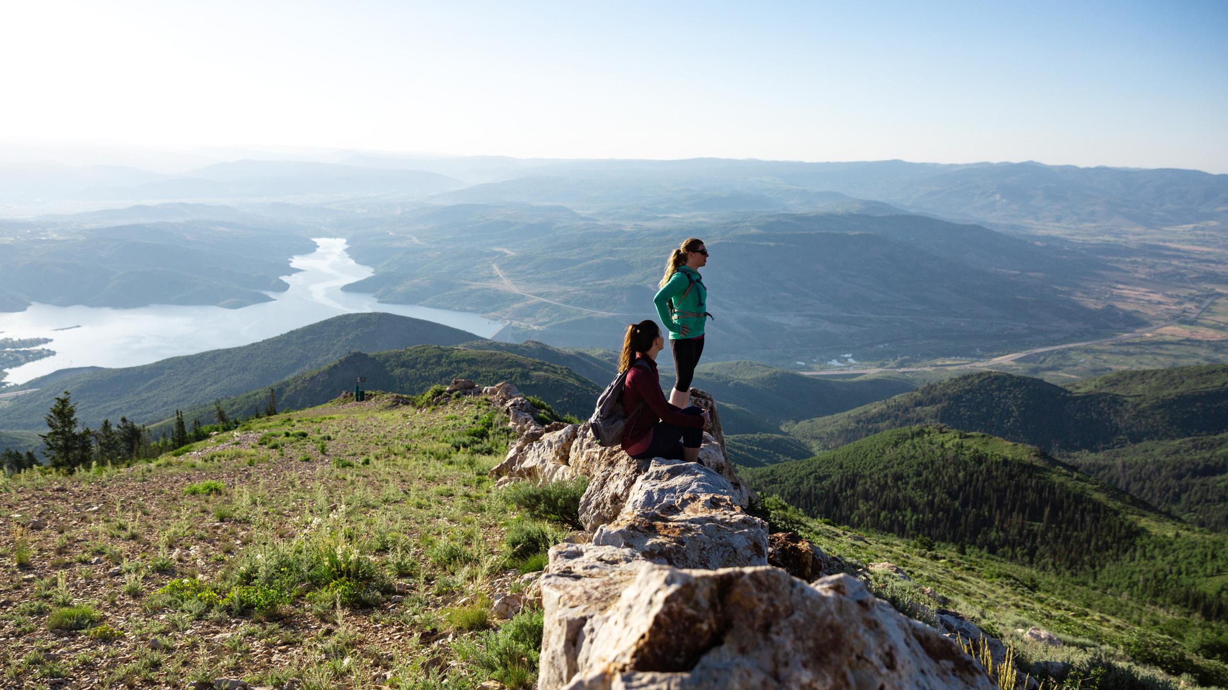 Two guests standing on a rock on top of a mountain at Deer Valley Resort