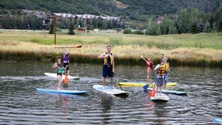 Campers doing stand up paddleboarding with a camp counselor