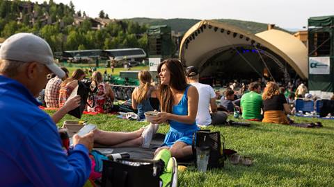 Group of concertgoers chatting with Snow Park Amphitheater in the background