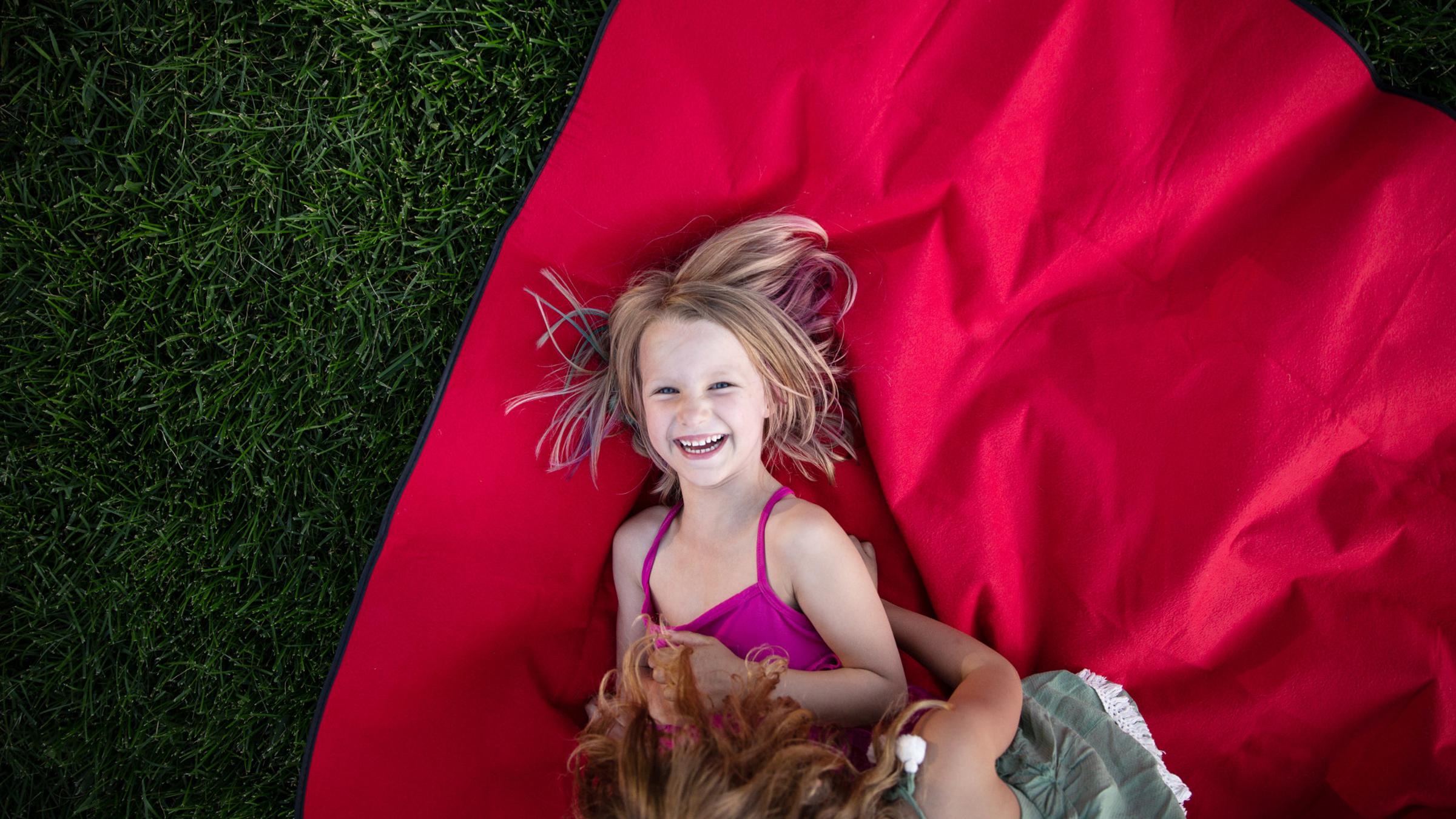 a little girl laying on a blanket laughing