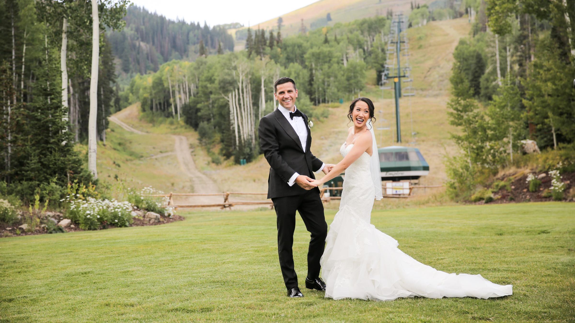 A bride and groom holding hands and smiling at the base of Empire