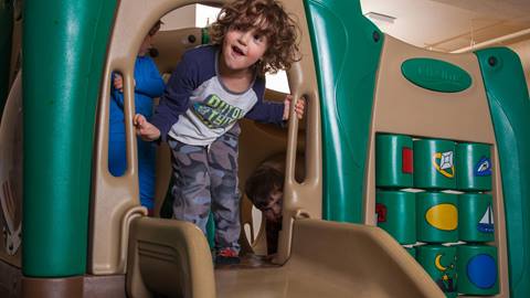 a little boy about to go down a slide laughing