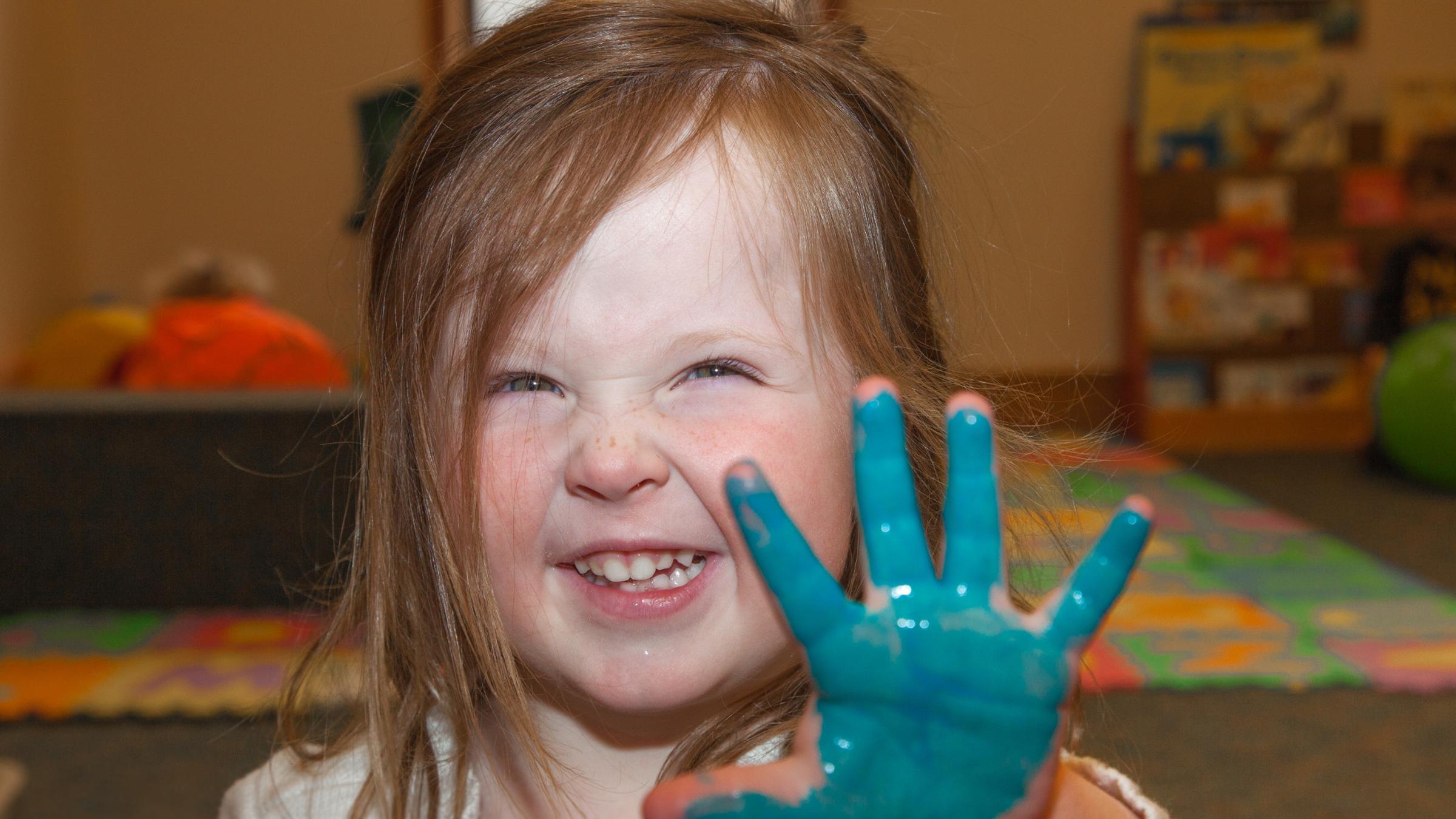 Young girl with a hand covered in blue paint