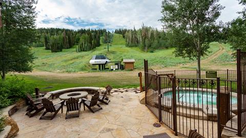 Grand Lodge outdoor firepit and hot tub with ski runs in the background in the summer