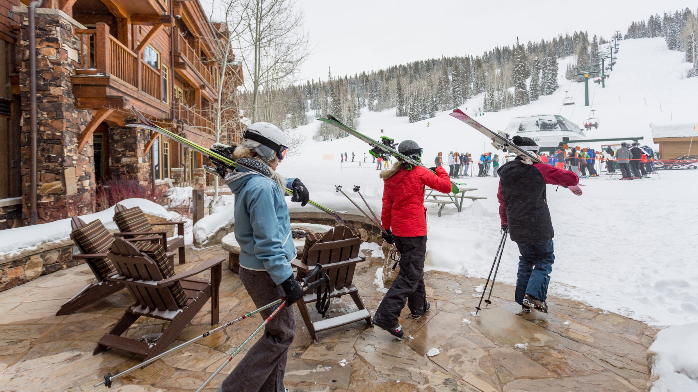 Three guests walking out from The Grand Lodge with their skis to go skiing